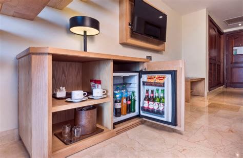 Imagen de minibar con bebidas miniatura en habitación de hotel