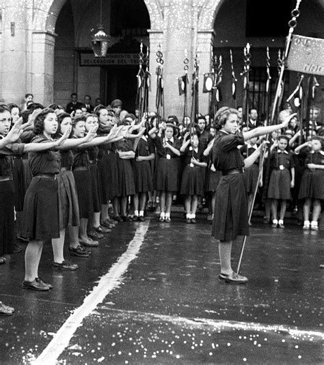 Fotografía histórica de un desfile con falangistas y Sección Femenina