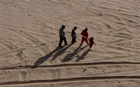familia migrante en el desierto, madre con niño y padre guiando
