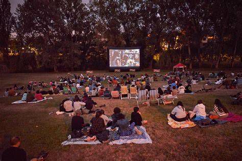 Proyección de cine al aire libre en plaza pública con público sentado